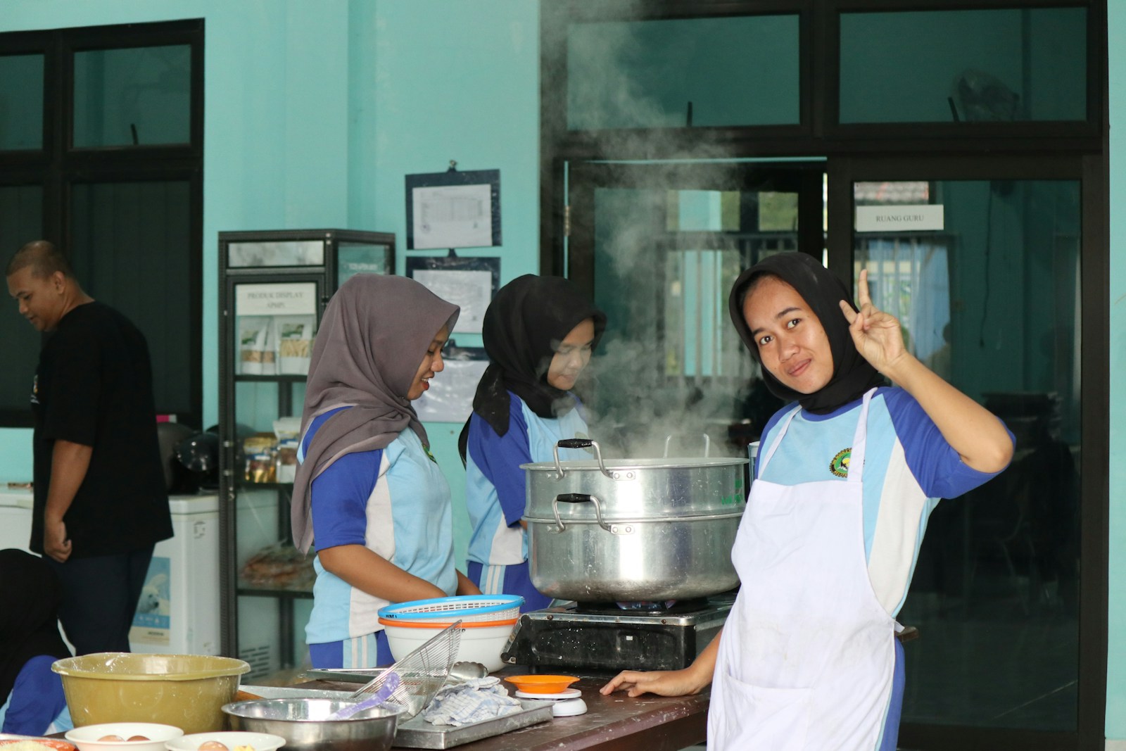Young people cooking and steaming food in a kitchen.